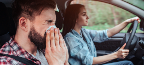 Vīrietis tīra degunu automašīnā.