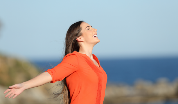 Sieviete brīvi elpo okeāna ainavā.